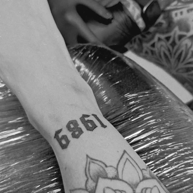 Tattoo van het jaartal 1989 in zwarte cijfers op een pols